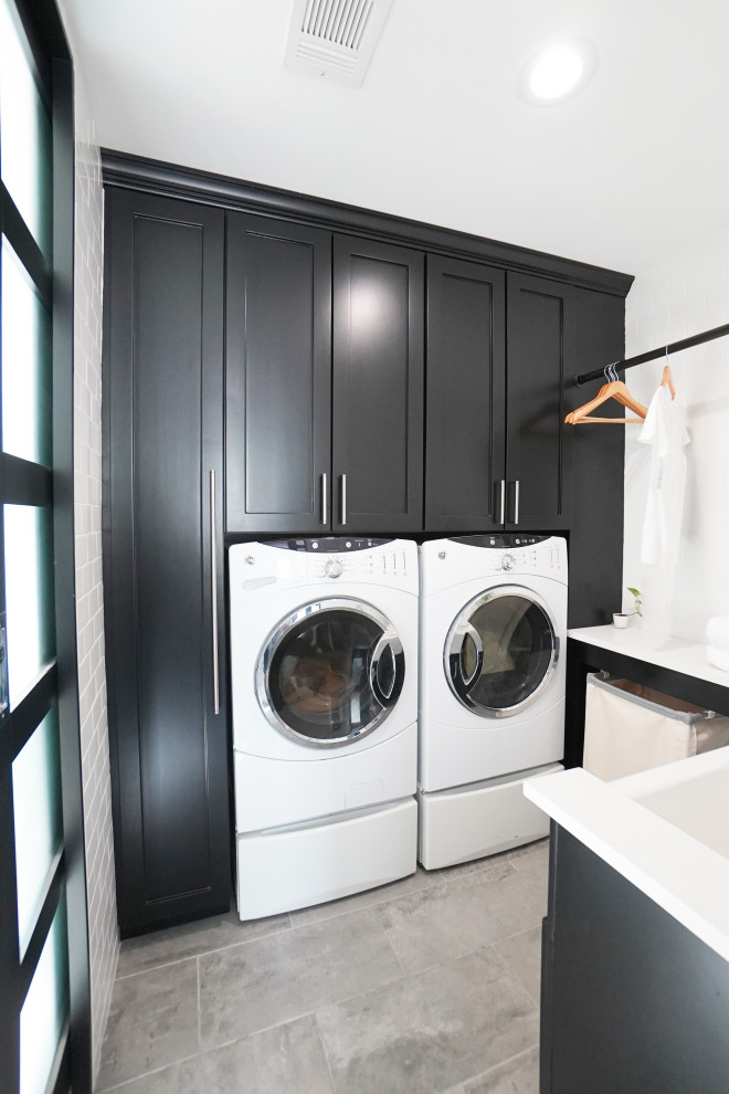 Immagine di una grande lavanderia minimal con ante lisce, ante nere, pareti grigie, pavimento in gres porcellanato e pavimento grigio