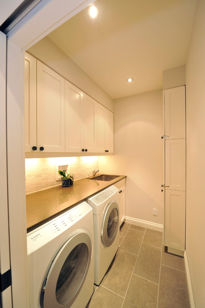 Medium sized contemporary single-wall separated utility room in Toronto with a submerged sink, white cabinets, composite countertops, white walls, ceramic flooring, a side by side washer and dryer and shaker cabinets.