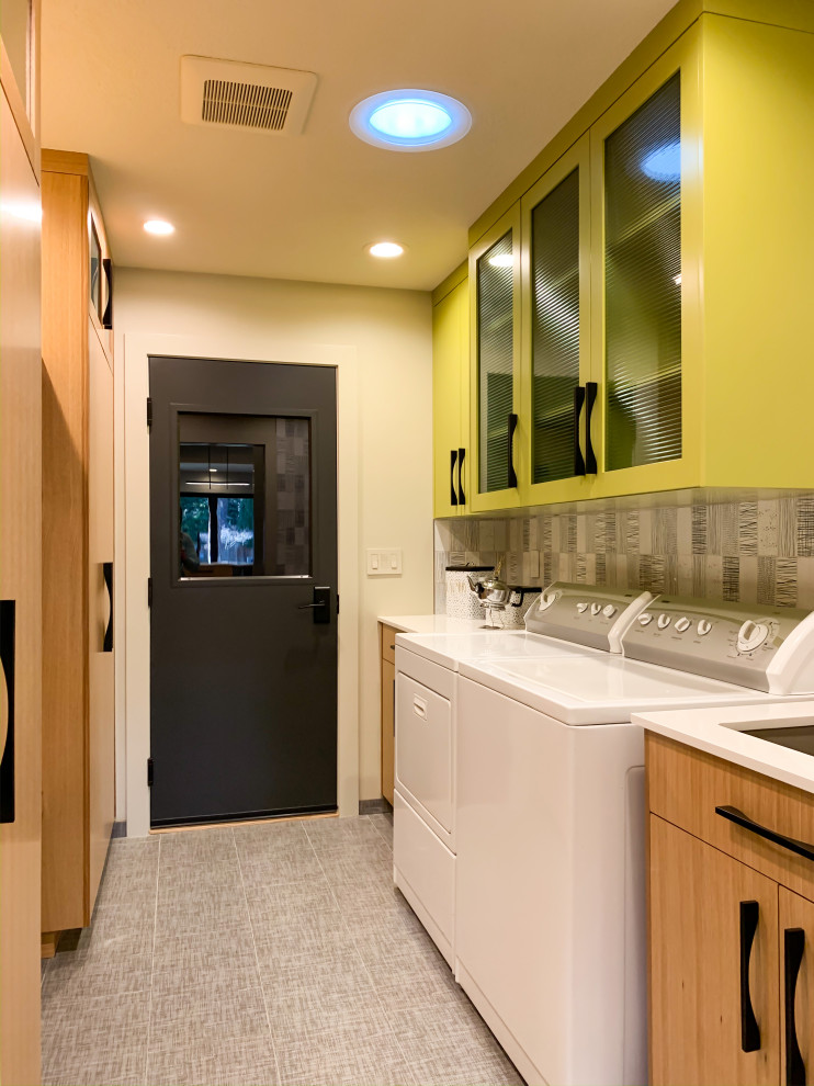 Multifunktionaler, Einzeiliger Moderner Hauswirtschaftsraum mit Unterbauwaschbecken, Glasfronten, grünen Schränken, weißer Wandfarbe, Waschmaschine und Trockner nebeneinander, grauem Boden und weißer Arbeitsplatte in Seattle