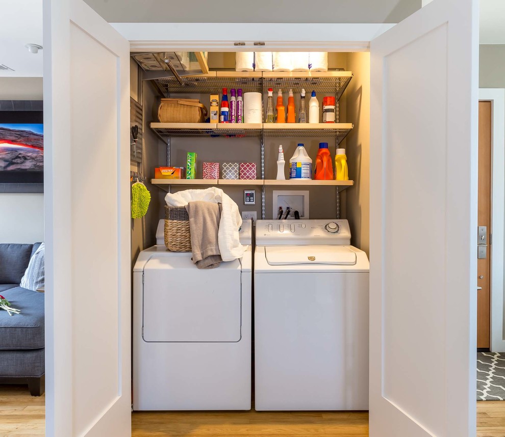 Photo of a small contemporary single-wall laundry cupboard in Los Angeles with open cabinets, beige walls, light hardwood flooring, a side by side washer and dryer and beige floors.