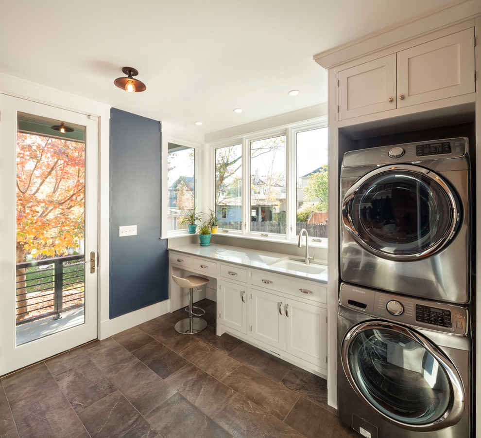 Foto di una piccola lavanderia minimal con lavello sottopiano, ante bianche, pareti blu, pavimento in gres porcellanato e lavatrice e asciugatrice a colonna