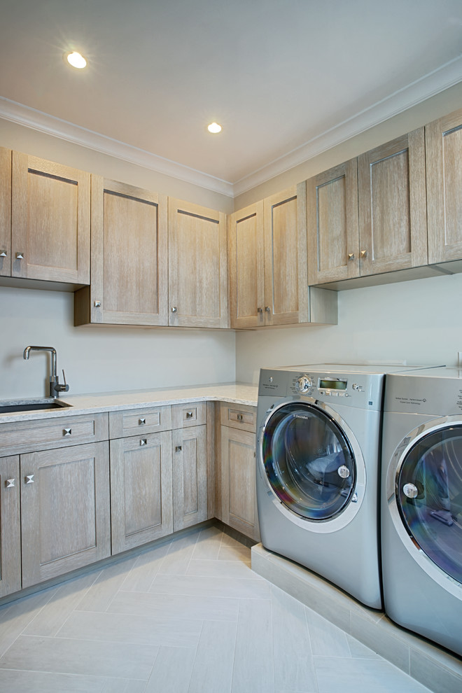 Klassischer Hauswirtschaftsraum mit hellen Holzschränken und Waschmaschine und Trockner nebeneinander in Boston