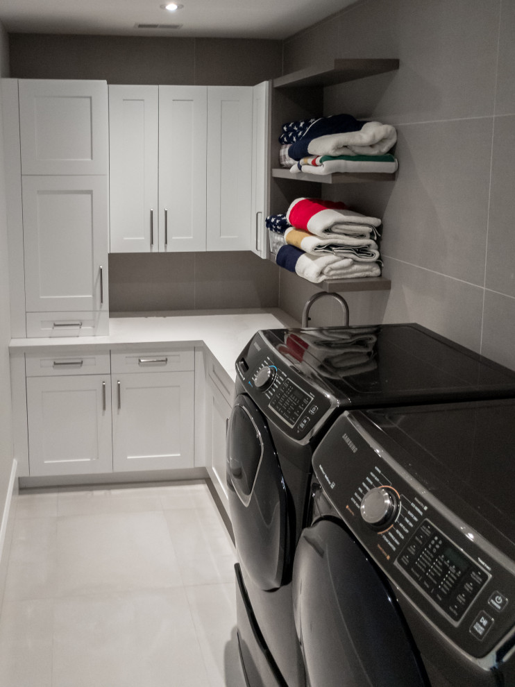 Inspiration för mellanstora moderna l-formade vitt tvättstugor enbart för tvätt, med en undermonterad diskho, skåp i shakerstil, vita skåp, bänkskiva i kvarts, vita väggar, klinkergolv i porslin, en tvättmaskin och torktumlare bredvid varandra och grått golv