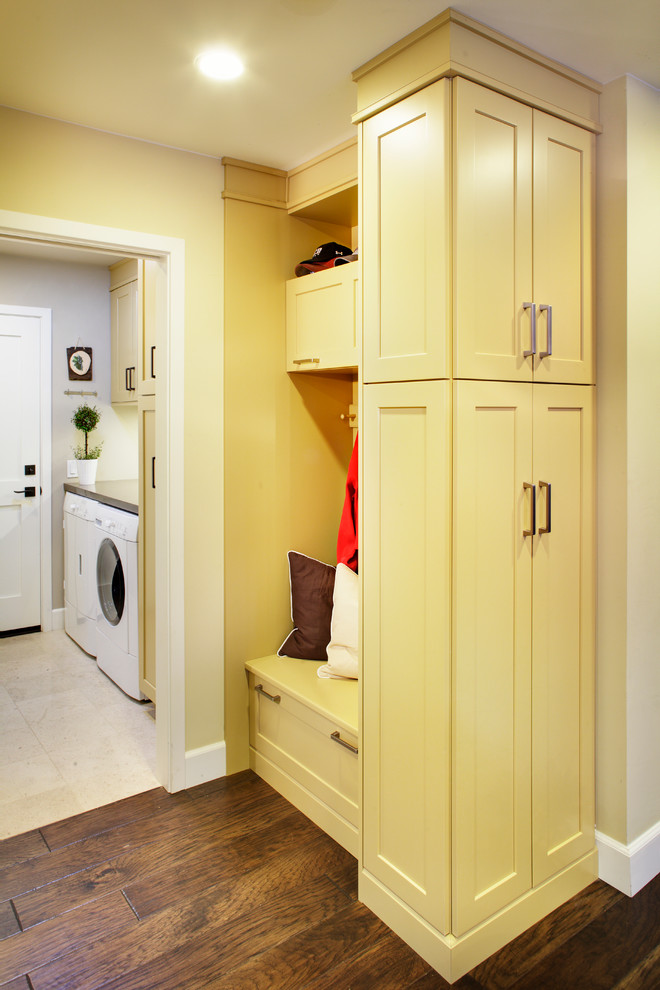 Immagine di una sala lavanderia chic di medie dimensioni con ante in stile shaker, ante gialle, top in quarzo composito, parquet scuro, lavatrice e asciugatrice affiancate e pareti beige