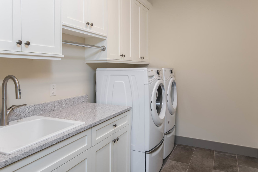 Large transitional single-wall porcelain tile and gray floor dedicated laundry room photo in Other with a drop-in sink, shaker cabinets, white cabinets, granite countertops, white walls, a side-by-side washer/dryer and gray countertops