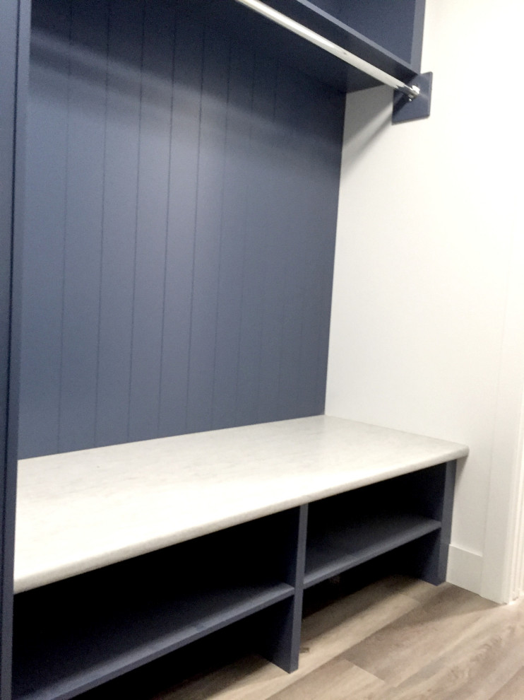 Bild på ett mellanstort funkis grå parallellt grått grovkök, med en nedsänkt diskho, blå skåp, laminatbänkskiva, vita väggar, vinylgolv, en tvättmaskin och torktumlare bredvid varandra och brunt golv