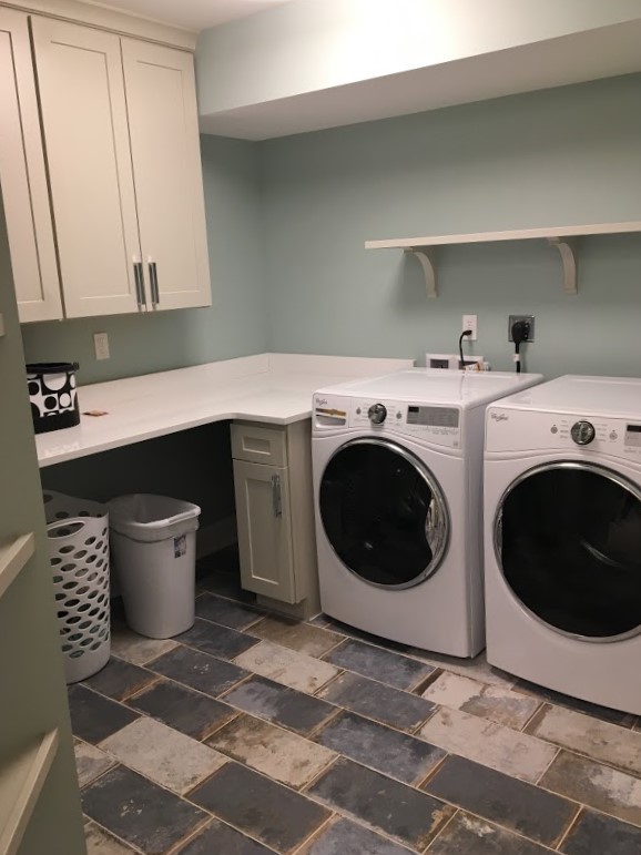 Bild på en mellanstor industriell l-formad liten tvättstuga, med beige skåp, blå väggar och en tvättmaskin och torktumlare bredvid varandra