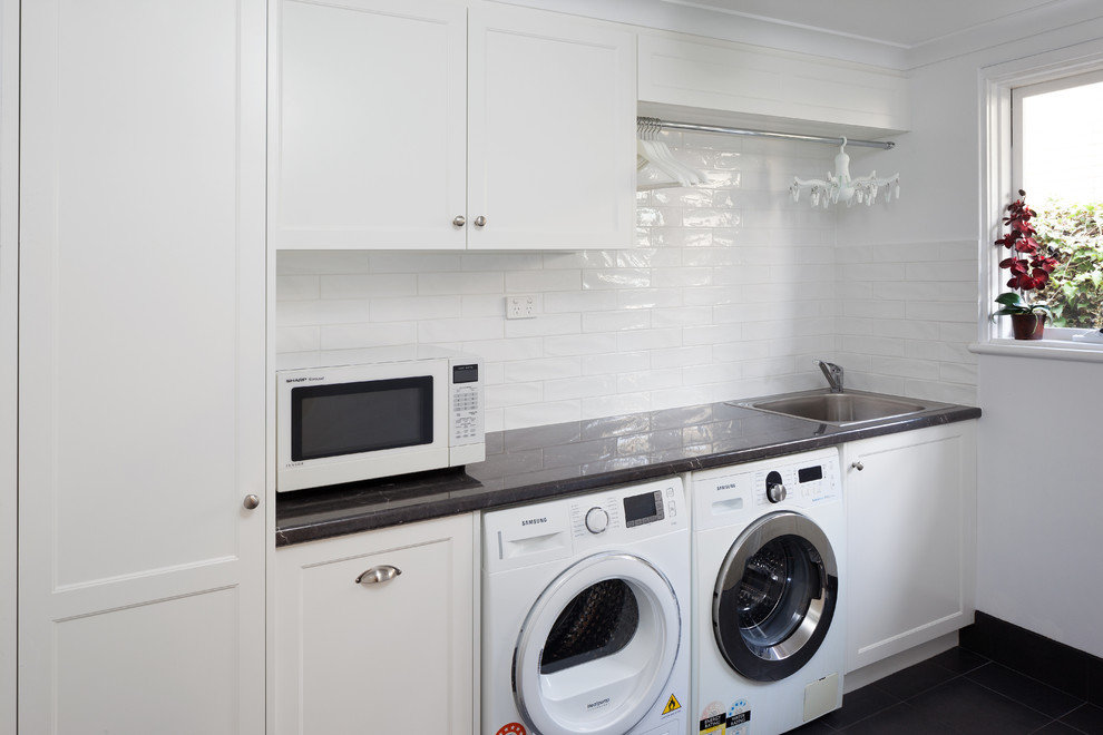 Immagine di una lavanderia moderna con lavello a vasca singola, top in laminato, pareti bianche, lavatrice e asciugatrice affiancate, ante in stile shaker, ante bianche e top nero