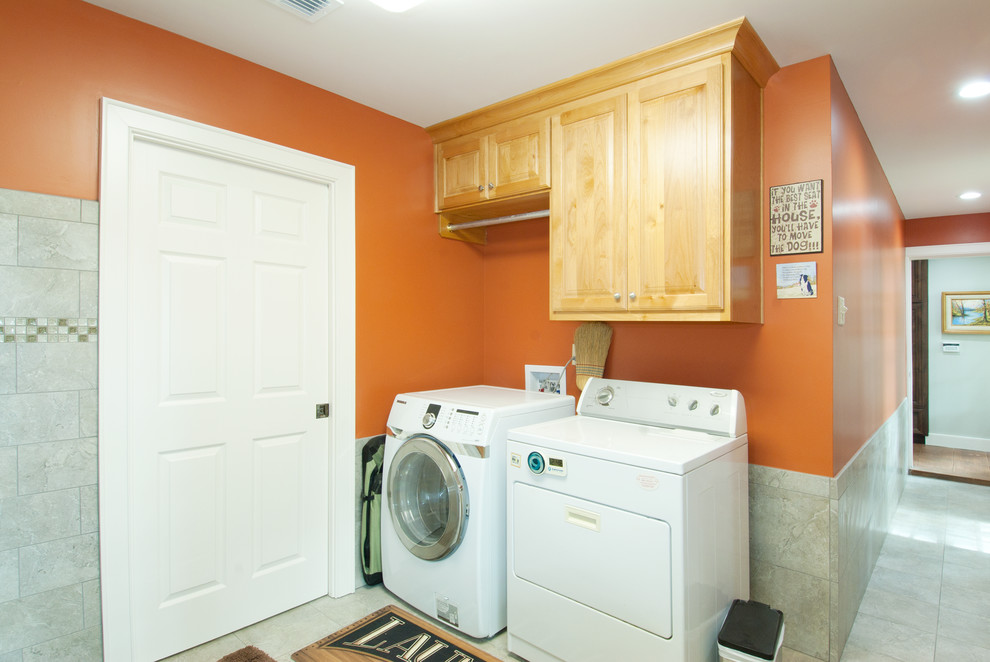 Imagen de cuarto de lavado en L clásico con armarios con paneles con relieve, puertas de armario de madera clara, encimera de granito, parades naranjas, suelo de baldosas de porcelana y lavadora y secadora juntas