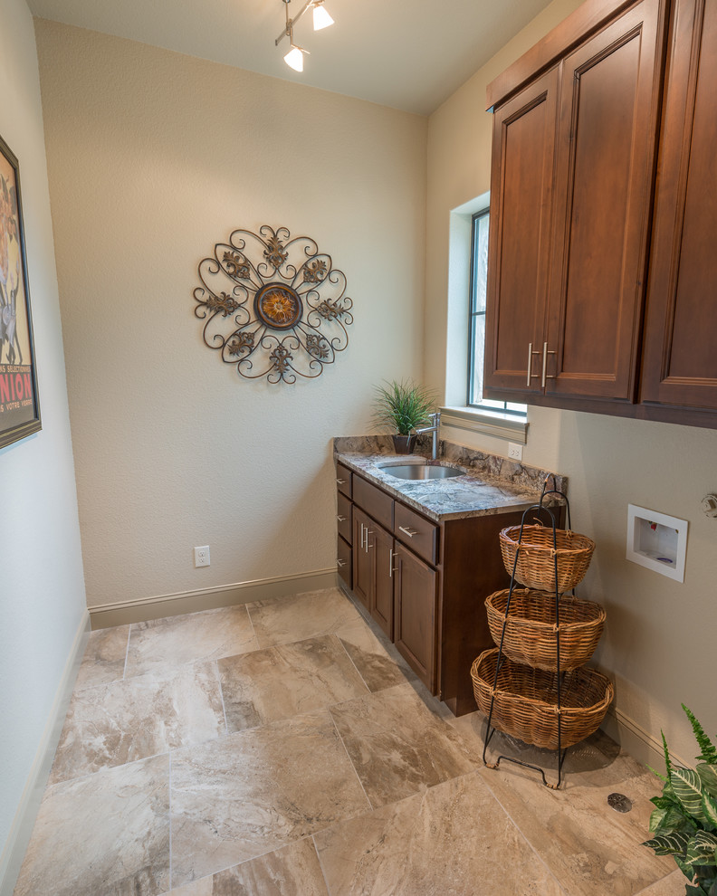 Immagine di una sala lavanderia chic di medie dimensioni con lavello sottopiano, ante con riquadro incassato, ante in legno bruno, top in granito, pareti beige e pavimento con piastrelle in ceramica