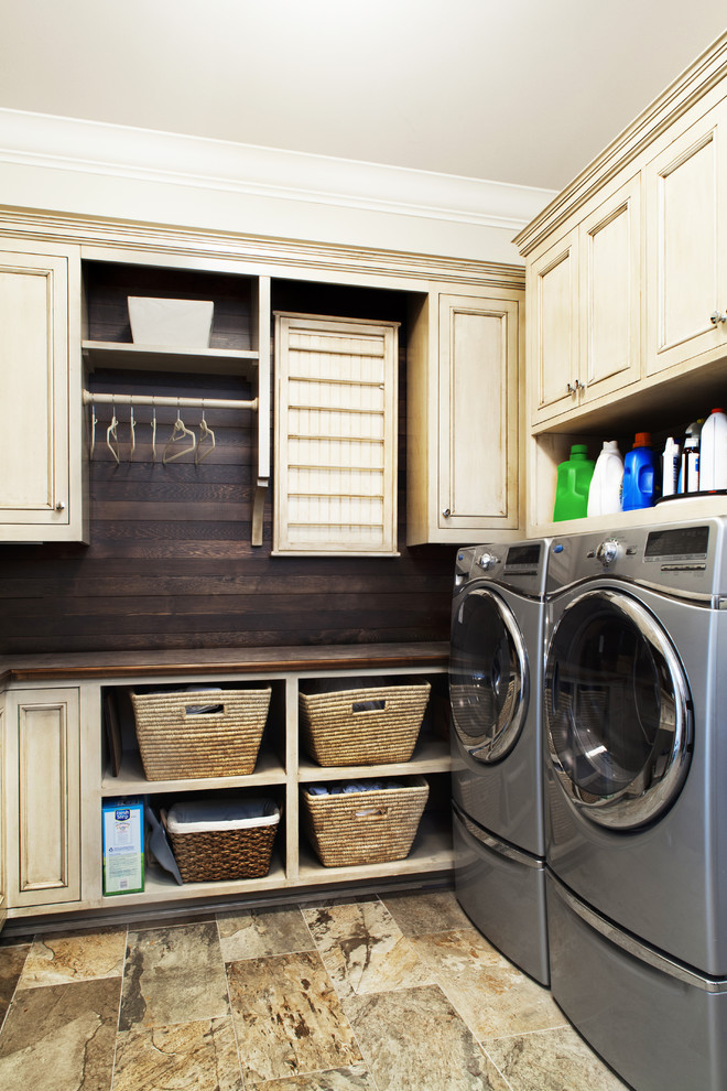 Foto på en vintage bruna tvättstuga, med beige skåp, en tvättmaskin och torktumlare bredvid varandra, luckor med infälld panel, klinkergolv i porslin och träbänkskiva