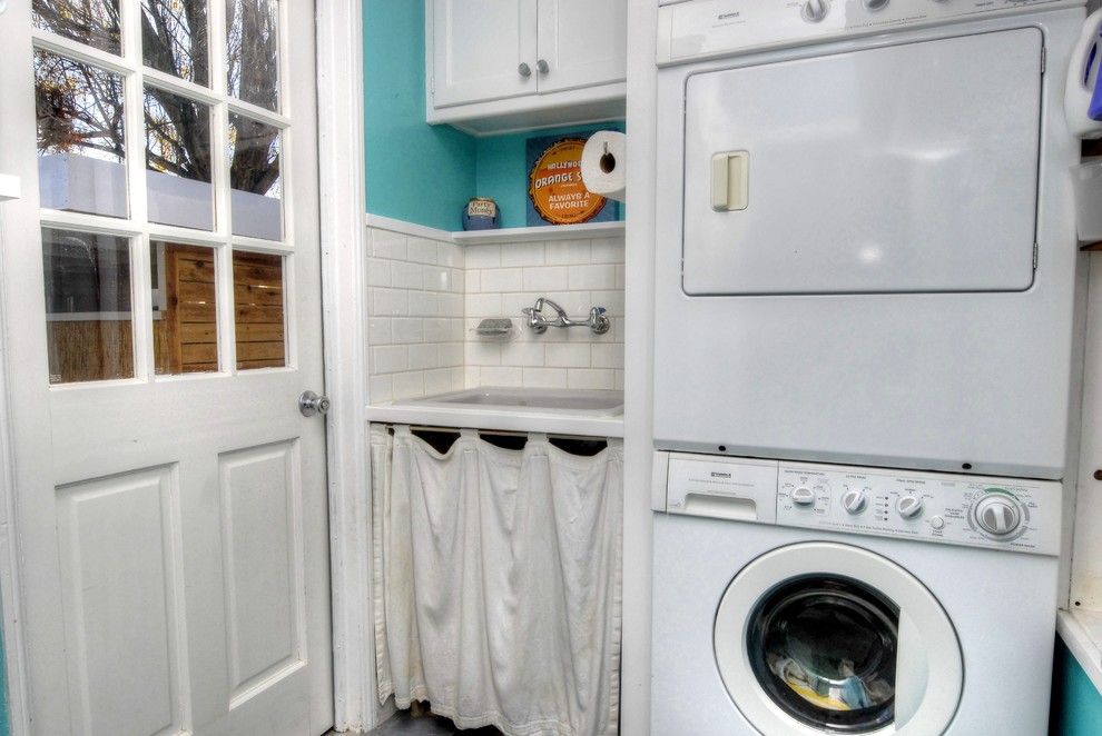 Zweizeilige, Mittelgroße Moderne Waschküche mit Unterbauwaschbecken, Schrankfronten mit vertiefter Füllung, weißen Schränken, blauer Wandfarbe, Schieferboden und Waschmaschine und Trockner gestapelt in Denver