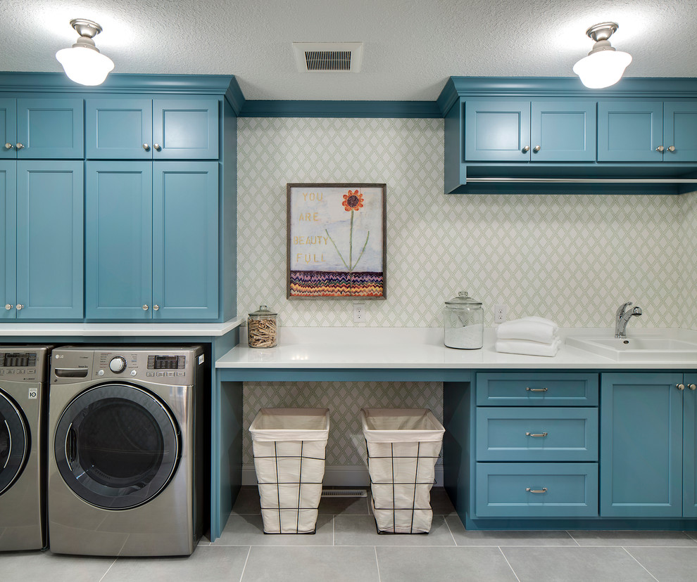 Einzeilige, Geräumige Moderne Waschküche mit blauen Schränken, Waschmaschine und Trockner nebeneinander, Einbauwaschbecken, Schrankfronten im Shaker-Stil, Marmor-Arbeitsplatte, grauer Wandfarbe und Schieferboden in Minneapolis