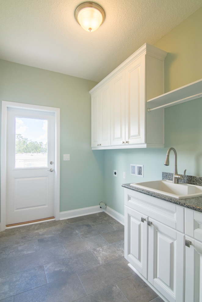 Example of a mid-sized farmhouse single-wall porcelain tile and gray floor utility room design in Jacksonville with a single-bowl sink, shaker cabinets, white cabinets, wood countertops, gray walls, a side-by-side washer/dryer and white countertops