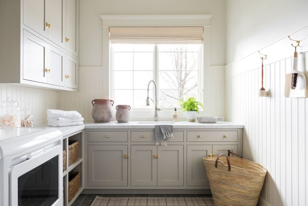 Inspiration för stora maritima l-formade flerfärgat tvättstugor enbart för tvätt, med grå skåp, marmorbänkskiva, vita väggar, klinkergolv i keramik, en tvättmaskin och torktumlare bredvid varandra och grått golv