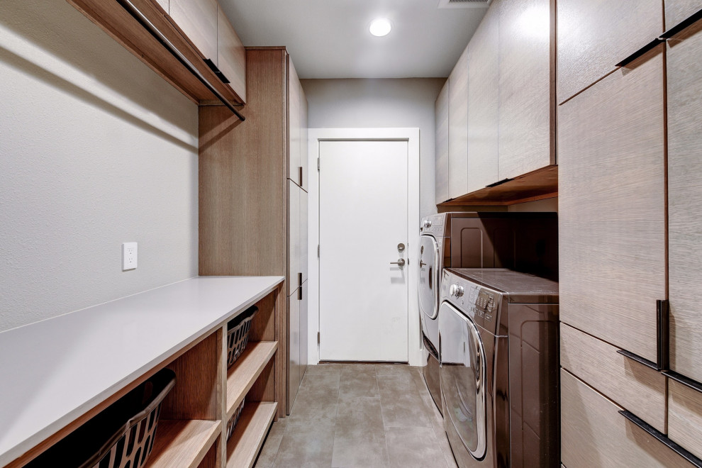 Immagine di una piccola sala lavanderia design con ante lisce, ante in legno chiaro, top in quarzo composito, pavimento con piastrelle in ceramica, lavatrice e asciugatrice affiancate, pavimento grigio e top bianco
