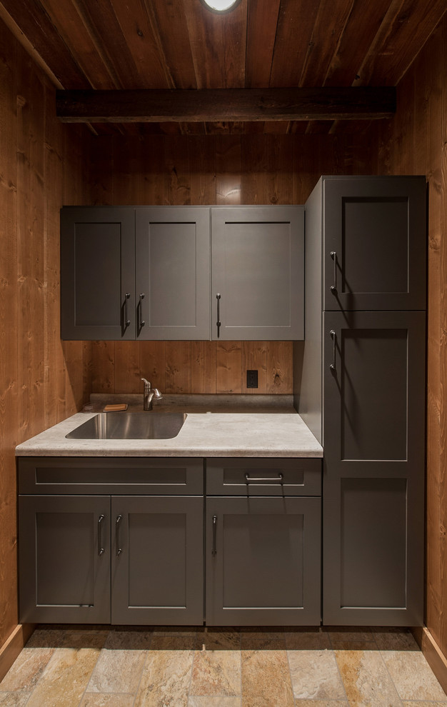 Inspiration for a mid-sized rustic single-wall laundry room remodel in Minneapolis with a single-bowl sink, flat-panel cabinets, gray cabinets, laminate countertops and wood backsplash