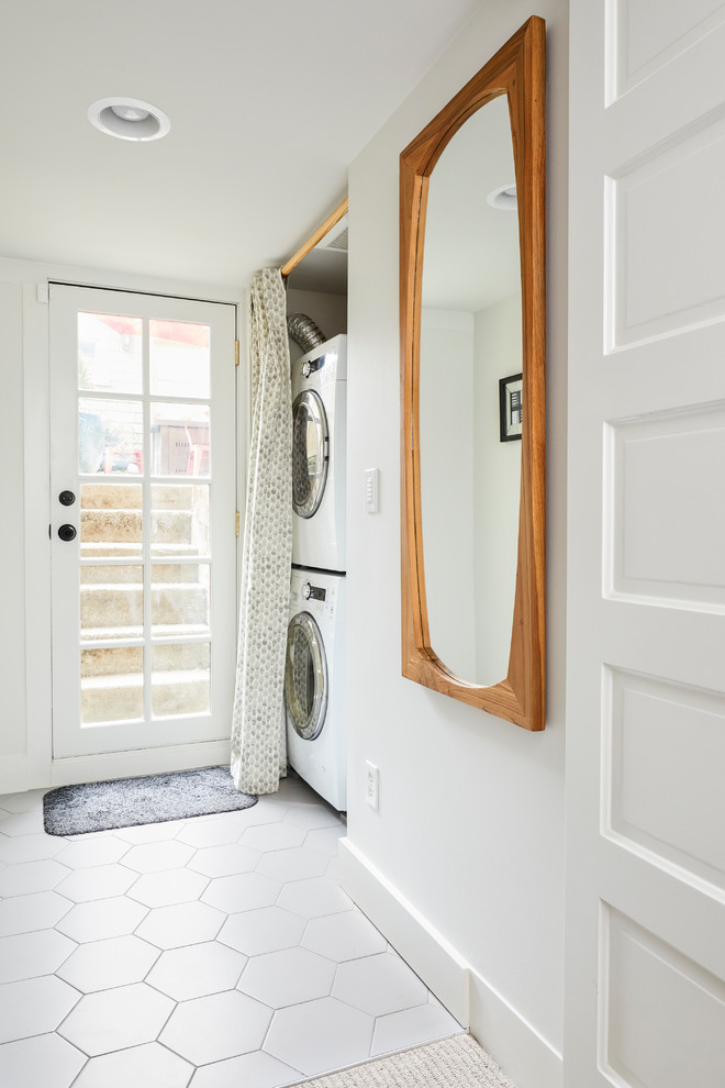 Imagen de armario lavadero de estilo americano con paredes blancas, suelo de baldosas de cerámica, suelo blanco y lavadora y secadora apiladas