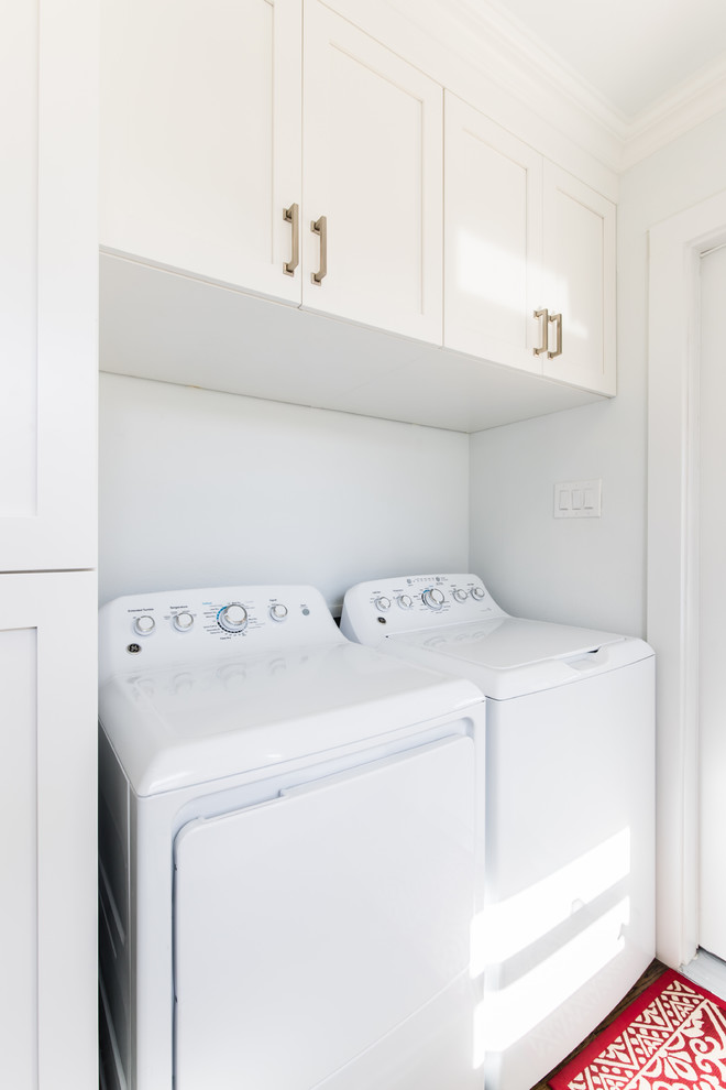Ispirazione per una piccola lavanderia multiuso stile americano con ante in stile shaker, ante bianche, pareti bianche, parquet chiaro e lavatrice e asciugatrice affiancate