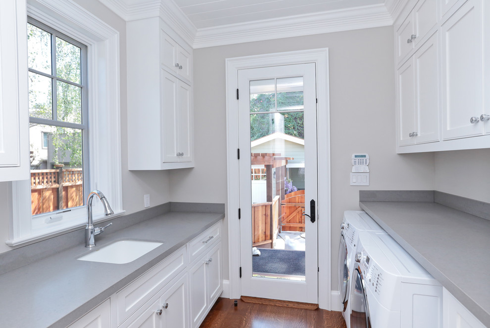 Inspiration for a traditional galley separated utility room in San Francisco with a submerged sink, flat-panel cabinets, white cabinets, engineered stone countertops, medium hardwood flooring and a side by side washer and dryer.