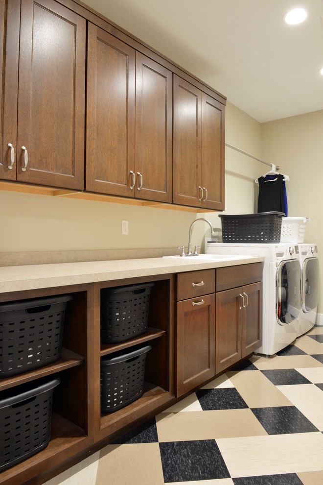 Inspiration for a large craftsman single-wall linoleum floor dedicated laundry room remodel in Other with a drop-in sink, shaker cabinets, laminate countertops, beige walls, a side-by-side washer/dryer and dark wood cabinets