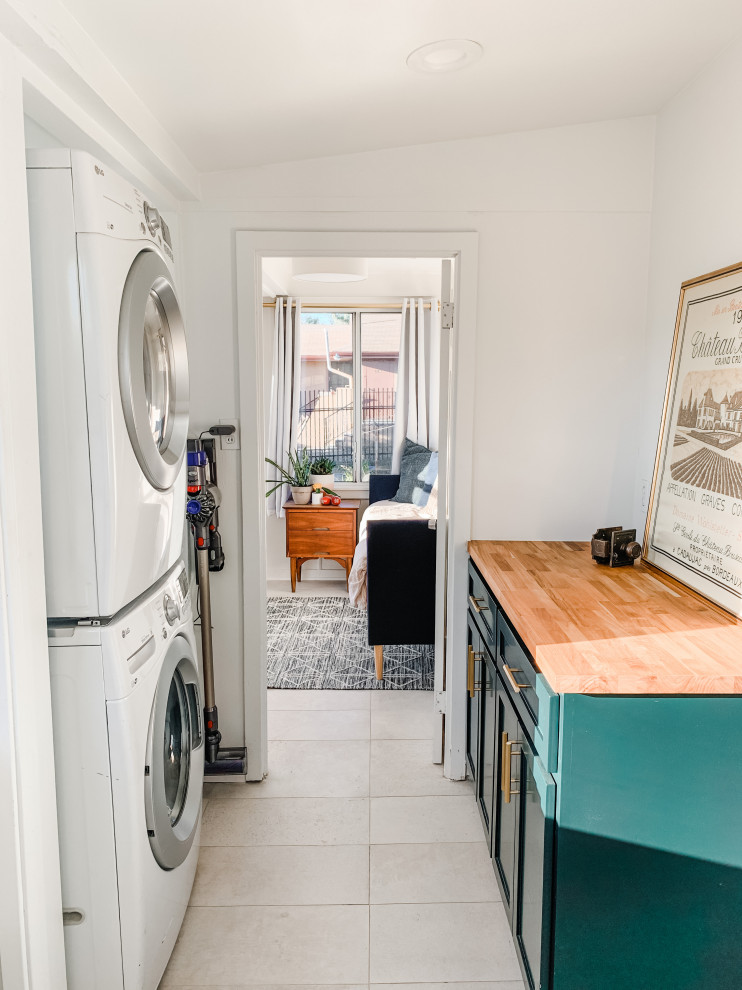 Foto på en liten amerikansk parallell tvättstuga enbart för tvätt, med skåp i shakerstil, gröna skåp, träbänkskiva, vita väggar, klinkergolv i porslin, en tvättpelare och grått golv