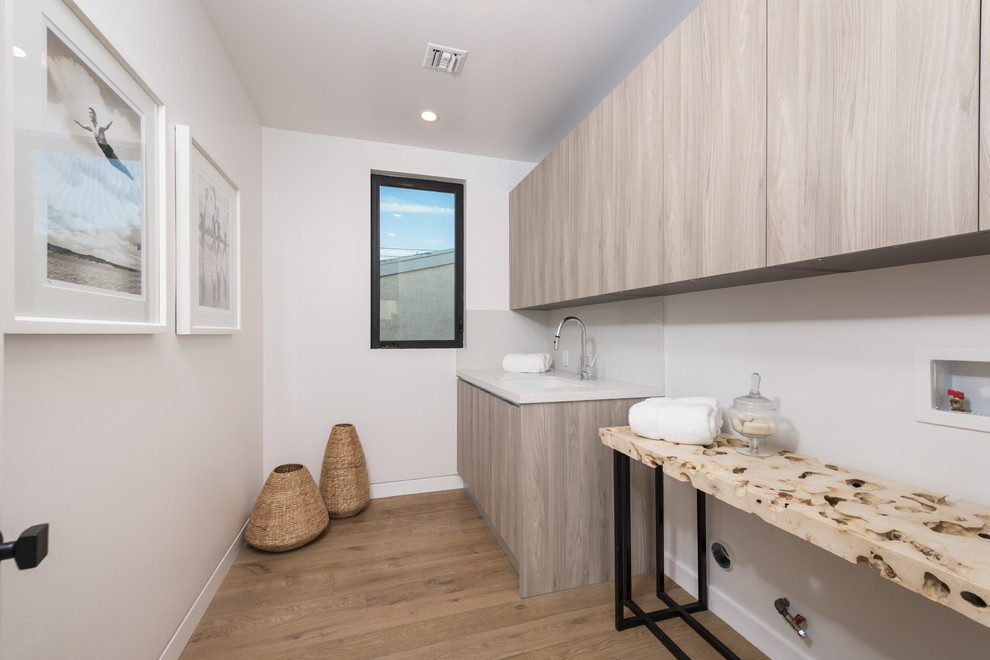 Multifunktionaler, Einzeiliger Moderner Hauswirtschaftsraum mit Unterbauwaschbecken, weißer Wandfarbe und hellem Holzboden in Los Angeles