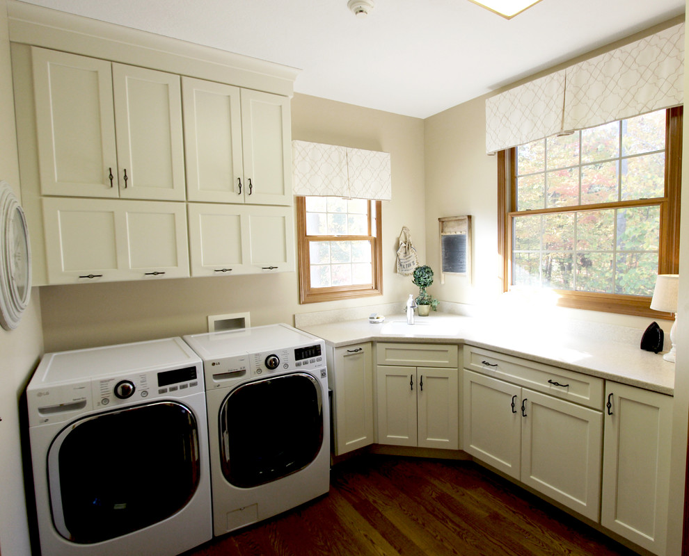 Medium sized traditional l-shaped separated utility room in Cleveland with an utility sink, flat-panel cabinets, dark wood cabinets, composite countertops, beige walls, medium hardwood flooring and a side by side washer and dryer.