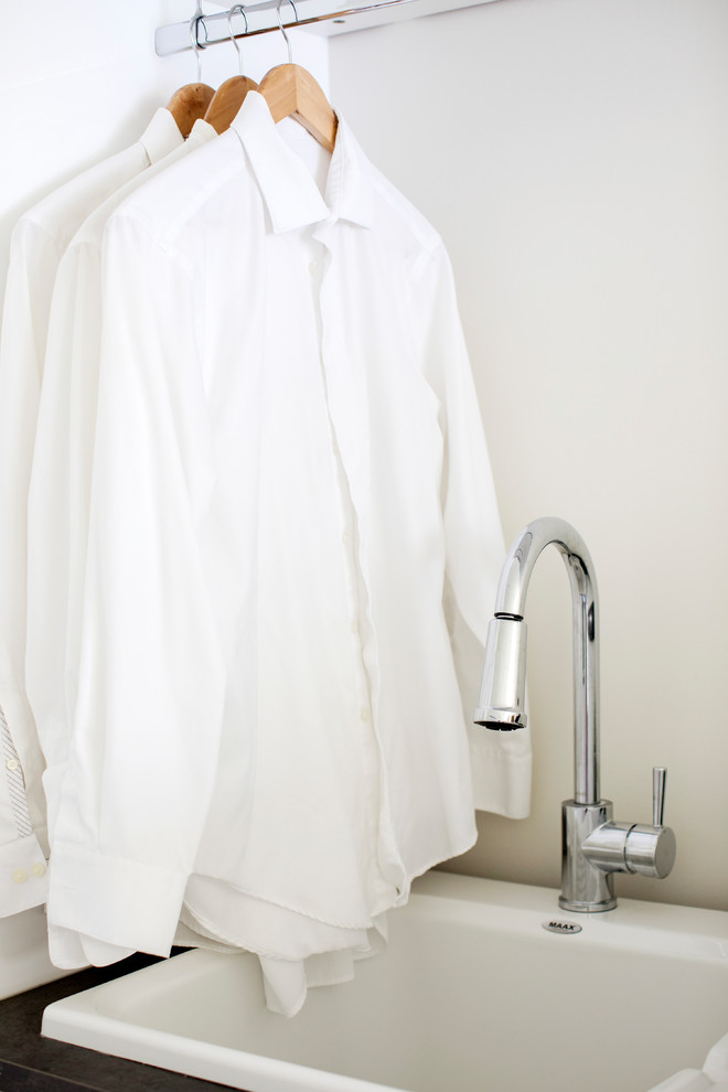 Esempio di una lavanderia multiuso design con lavello da incasso, ante lisce, ante bianche, top in laminato e pareti bianche