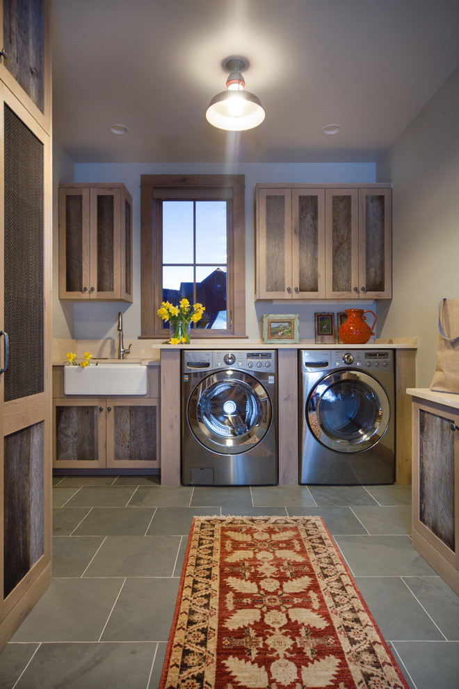 This is an example of a large transitional l-shaped dedicated laundry room in Denver with a farmhouse sink, recessed-panel cabinets, quartz benchtops, beige walls, slate floors, a side-by-side washer and dryer and dark wood cabinets.