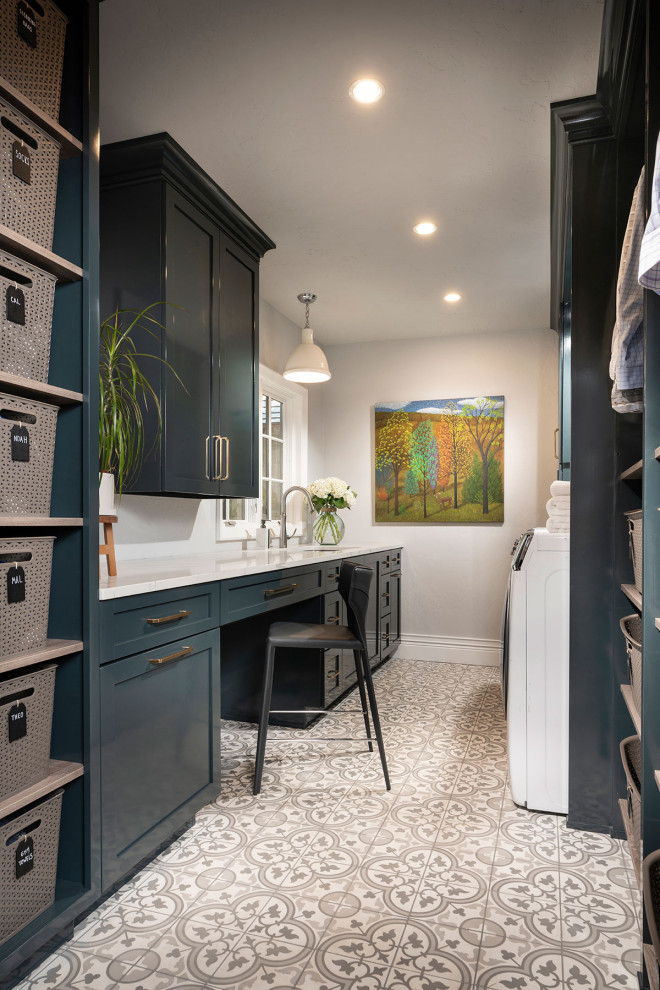 Medium sized traditional galley separated utility room in Other with a submerged sink, blue cabinets, engineered stone countertops, grey walls, porcelain flooring, a side by side washer and dryer, shaker cabinets, grey floors and white worktops.