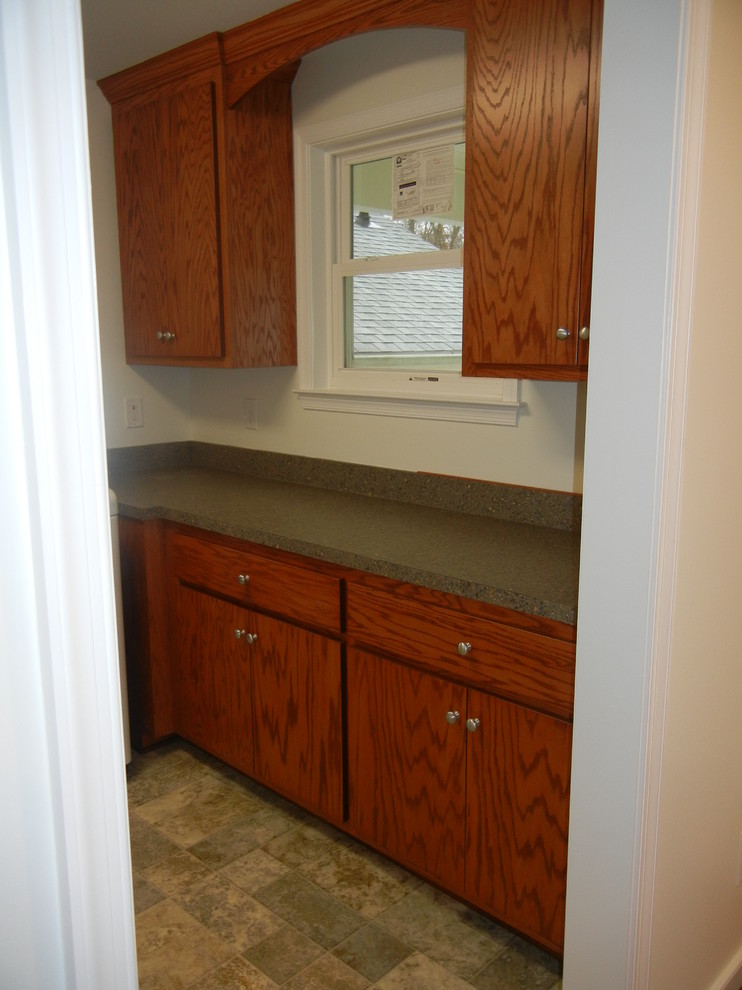 Example of a small l-shaped laundry room design in Other with flat-panel cabinets, medium tone wood cabinets, laminate countertops, white walls and a side-by-side washer/dryer