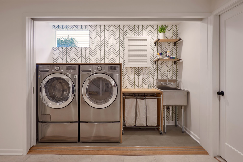Diseño de armario lavadero lineal tradicional renovado de tamaño medio con pila para lavar, encimera de madera, suelo de cemento, lavadora y secadora juntas, suelo verde y paredes blancas