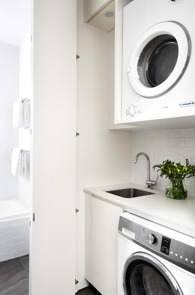 Foto di una piccola lavanderia multiuso minimalista con lavello sottopiano, ante bianche, top in quarzo composito, pareti bianche, pavimento in gres porcellanato, pavimento grigio e top bianco