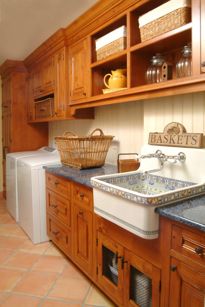 Idéer för att renovera en mellanstor amerikansk grå linjär grått tvättstuga enbart för tvätt, med en rustik diskho, skåp i mellenmörkt trä, laminatbänkskiva, beige väggar, klinkergolv i terrakotta, en tvättmaskin och torktumlare bredvid varandra, rött golv och luckor med upphöjd panel