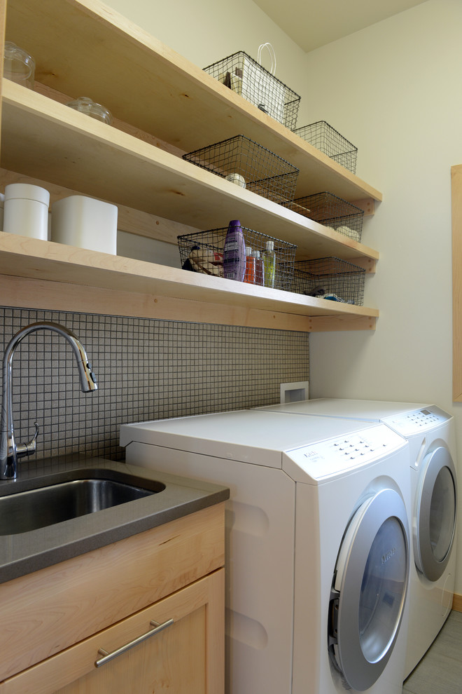 Bild på en liten funkis tvättstuga enbart för tvätt, med en undermonterad diskho, skåp i shakerstil, skåp i ljust trä, bänkskiva i kvartsit, vita väggar och en tvättmaskin och torktumlare bredvid varandra