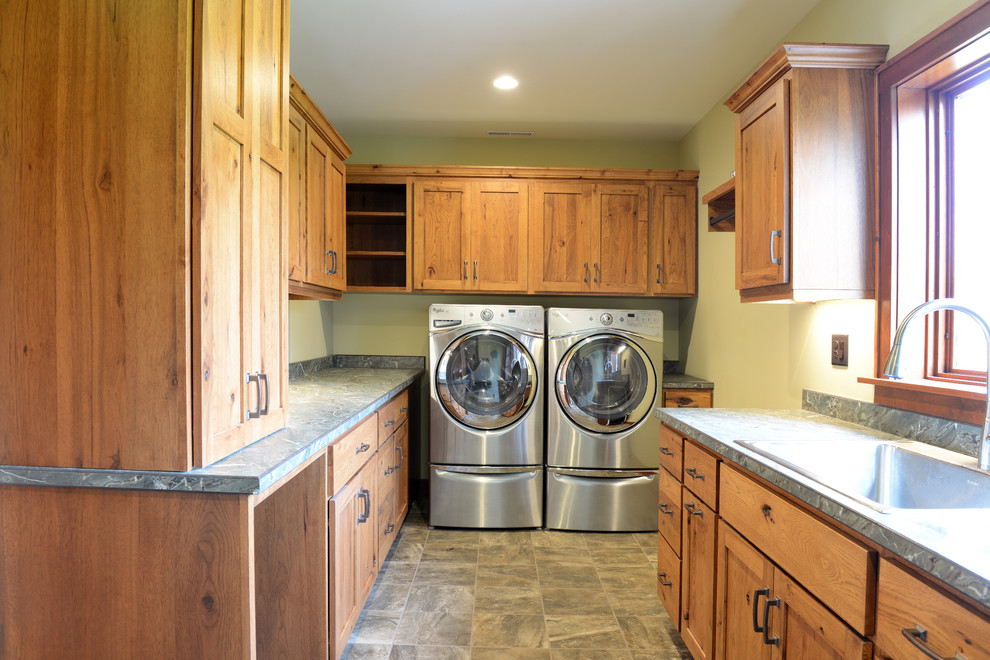 Immagine di una sala lavanderia classica di medie dimensioni con lavello a vasca singola, ante in stile shaker, ante in legno scuro, top in laminato, pareti gialle e lavatrice e asciugatrice affiancate