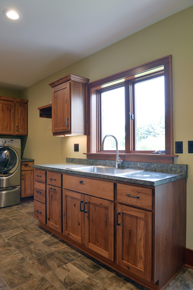 Mid-sized elegant u-shaped dedicated laundry room photo in Other with a single-bowl sink, shaker cabinets, medium tone wood cabinets, laminate countertops, a side-by-side washer/dryer and beige walls