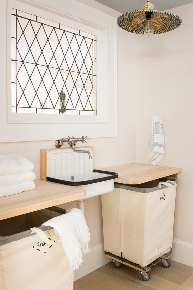 Immagine di una lavanderia costiera con top in legno, pareti beige, pavimento in legno massello medio, pavimento marrone e top beige