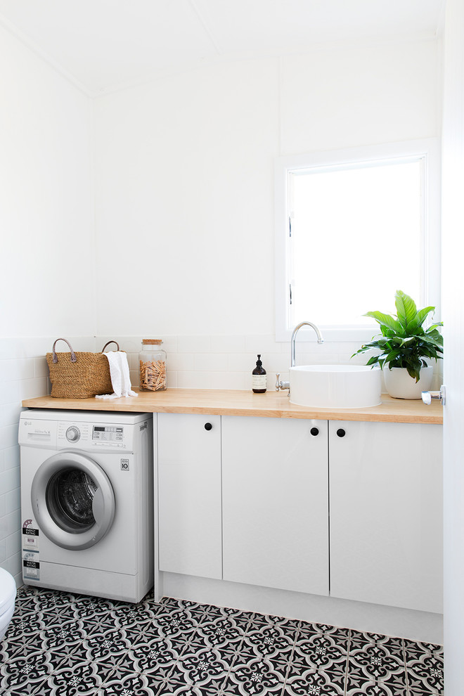 Idéer för maritima linjära beige tvättstugor enbart för tvätt, med släta luckor, vita skåp, träbänkskiva, vita väggar och flerfärgat golv