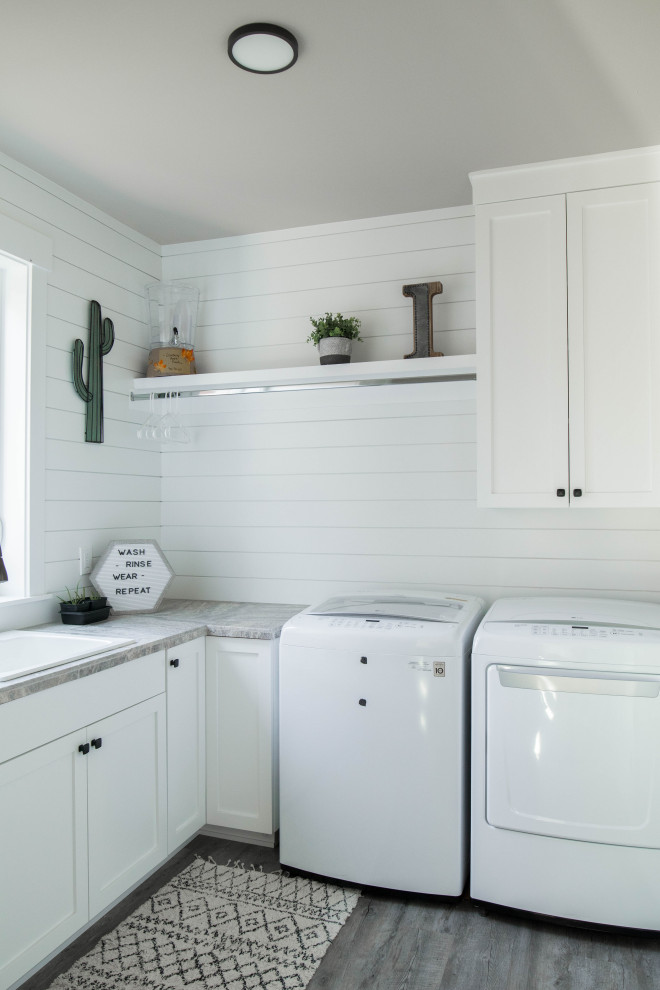 Dedicated laundry room - mid-sized craftsman l-shaped painted wood floor and gray floor dedicated laundry room idea in Portland with a drop-in sink, recessed-panel cabinets, white cabinets, limestone countertops, white walls, a side-by-side washer/dryer and gray countertops