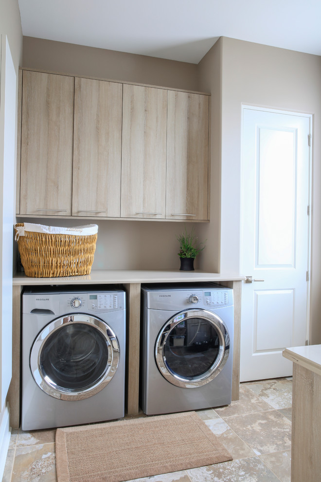 Bild på en mellanstor funkis tvättstuga enbart för tvätt, med släta luckor, skåp i ljust trä, bänkskiva i kvarts, beige väggar, klinkergolv i porslin och en tvättmaskin och torktumlare bredvid varandra
