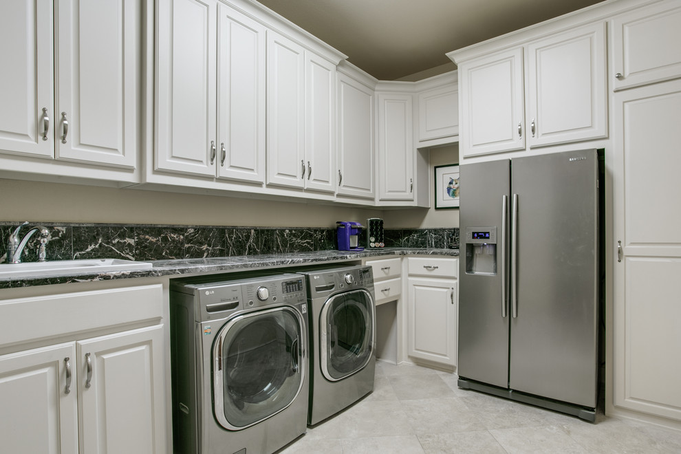 Foto di una lavanderia moderna con ante con bugna sagomata, ante bianche, top in marmo, pareti beige, pavimento in travertino, lavatrice e asciugatrice affiancate e lavello da incasso