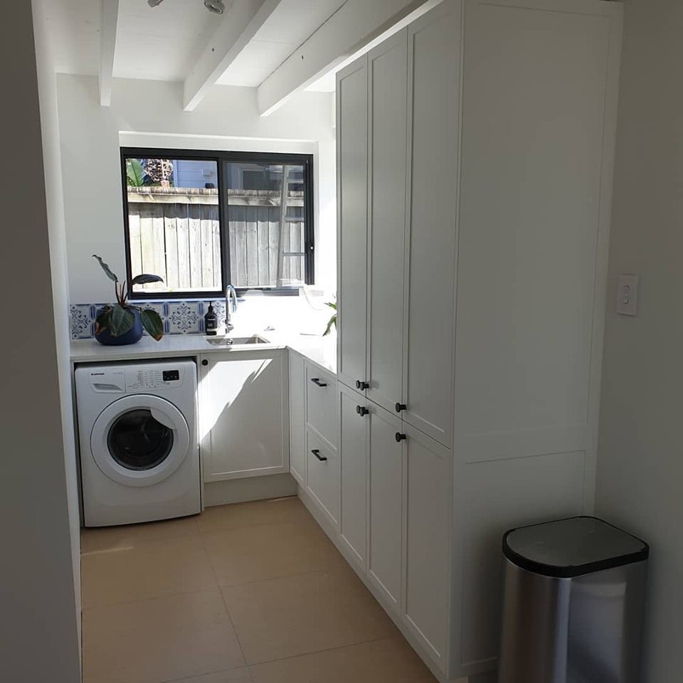 Inredning av en modern liten tvättstuga med garderob, med vita väggar och beiget golv