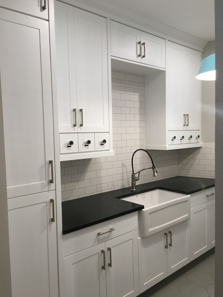 This is an example of a large contemporary utility room in Boise with a belfast sink, white cabinets, granite worktops, porcelain flooring and a side by side washer and dryer.