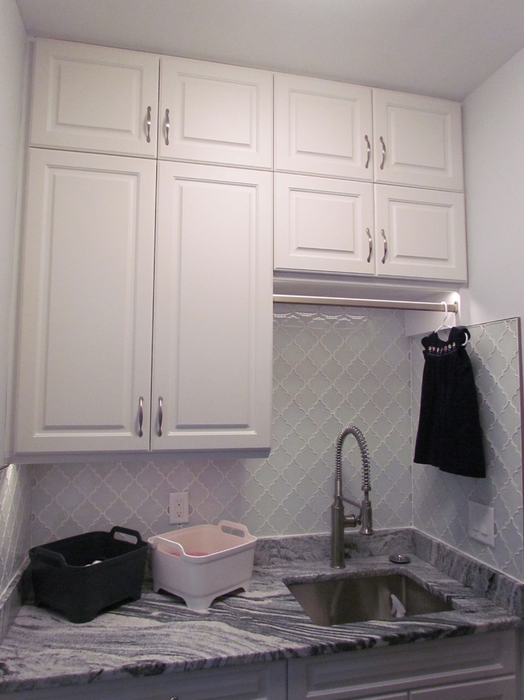 Immagine di una piccola lavanderia multiuso tradizionale con lavello sottopiano, ante con bugna sagomata, ante bianche, top in marmo e pareti bianche