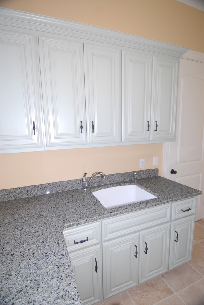 Example of a mid-sized classic l-shaped ceramic tile utility room design in Atlanta with raised-panel cabinets, white cabinets, beige walls, a side-by-side washer/dryer and an undermount sink