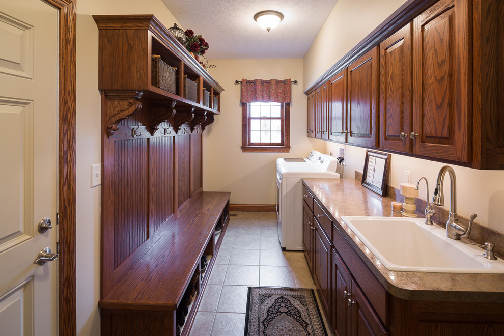 Utility room - small traditional galley utility room idea in Columbus with a single-bowl sink, raised-panel cabinets, medium tone wood cabinets, laminate countertops, beige walls and a side-by-side washer/dryer