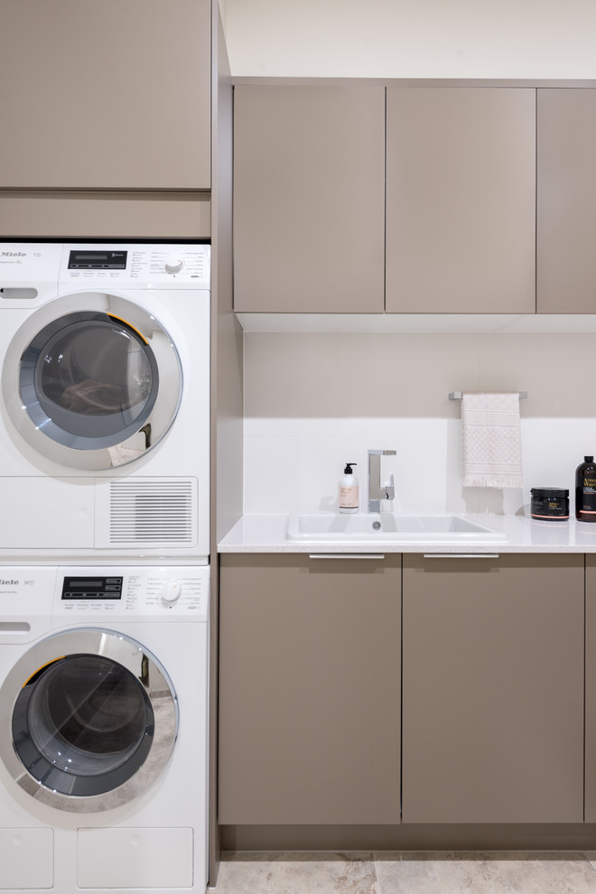 Esempio di una lavanderia moderna di medie dimensioni con pareti beige, lavatrice e asciugatrice a colonna e top beige