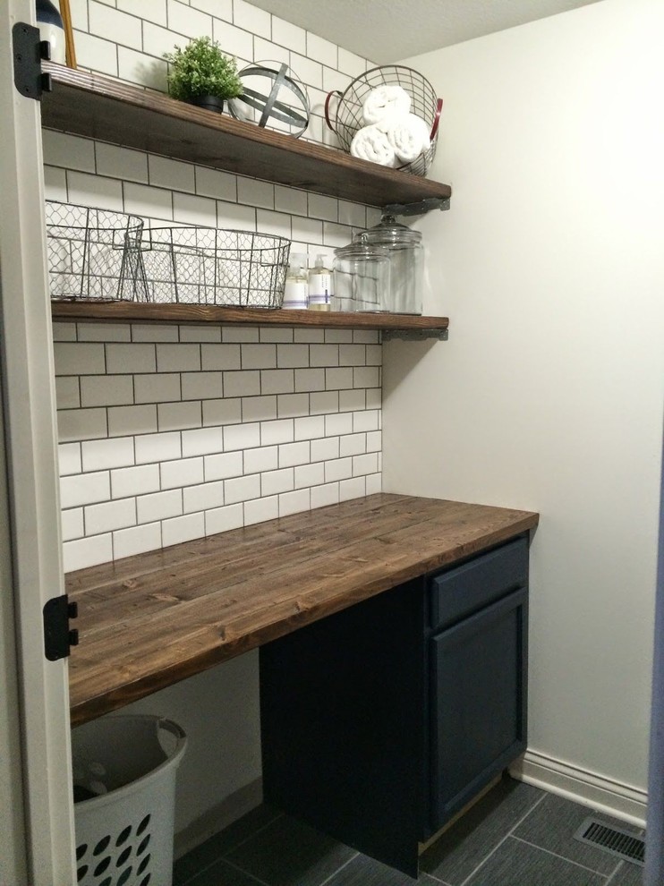 Idéer för mellanstora linjära brunt små tvättstugor, med luckor med infälld panel, blå skåp, träbänkskiva, vita väggar, klinkergolv i porslin, tvättmaskin och torktumlare byggt in i ett skåp och grått golv